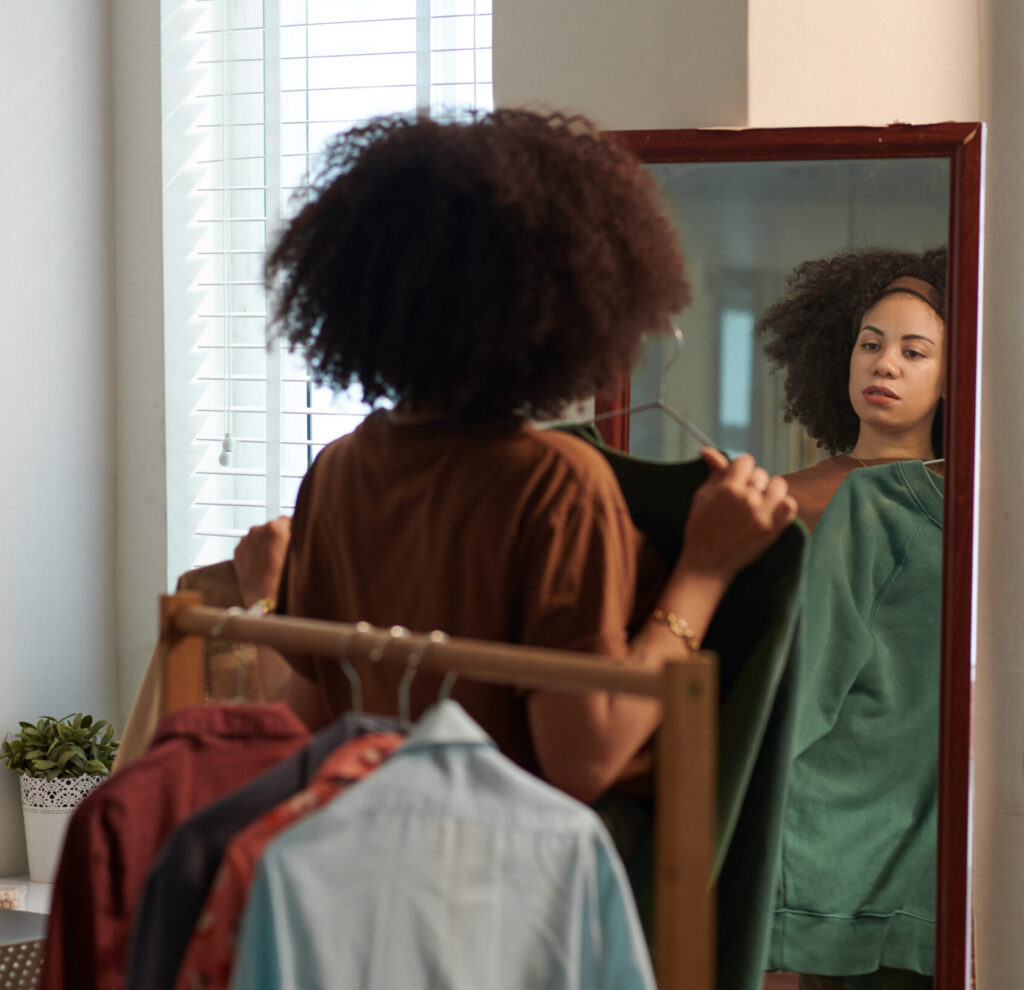 Woman at the mirror holding up a shirt